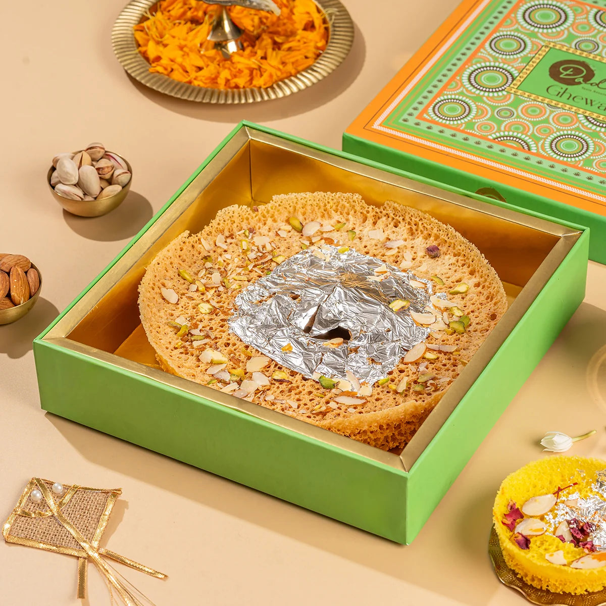 Chandini Ghewar 6-inch by Dadus, silver leaf and pistachio topping, in a green presentation gift box, with pistachios and almonds on the side