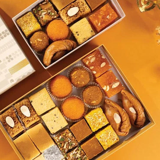Sixteen assorted Indian sweets from Almond House in open Diwali gift boxes, including kaju burfi, milk cake, badam halwa and motichoor laddu